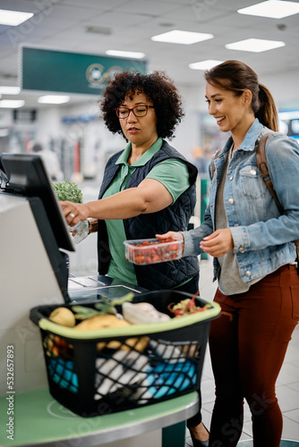 Canvas Print Supermarket worker assists buyer in using self-service till at checkout