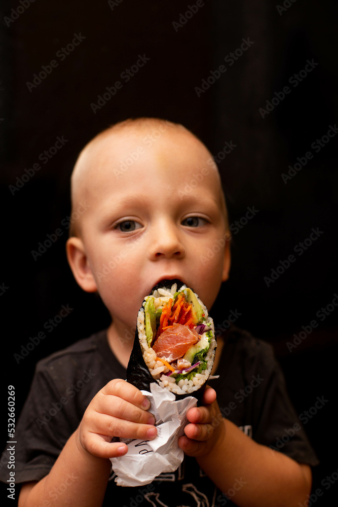 Naklejka premium Child eating Japanese food .