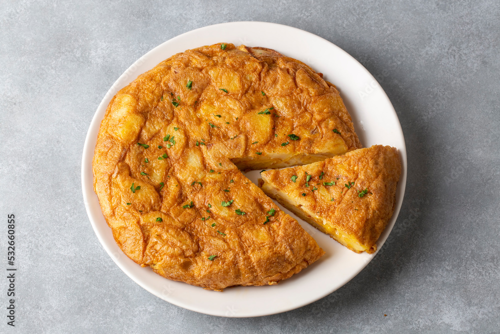 Spanish omelette with potatoes, typical spanish cuisine on gray concrete floor. Tortilla Espanola. Turkish name; Yumurtali patates Spanish omelette with potatoes, typical spanish cuisine on gray concrete floor. Tortilla Espanola. Turkish name; Yumurtali patates