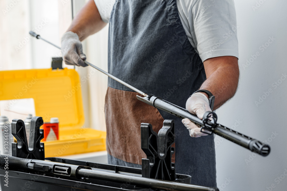 Close up of a gunsmith cleaning firearm barrel with ramrod brush - obrazy, fototapety, plakaty 
