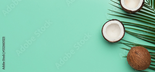Ripe coconuts and palm leaf on turquoise background with space for text, top view