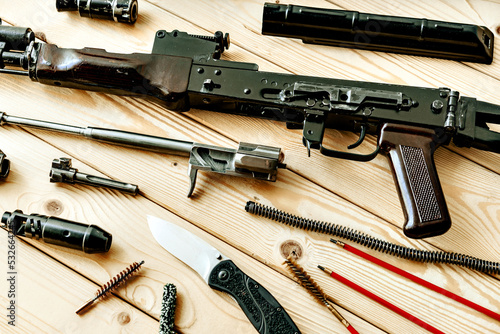 Disassembled rifle with cleaning tools on table of weapons workshop