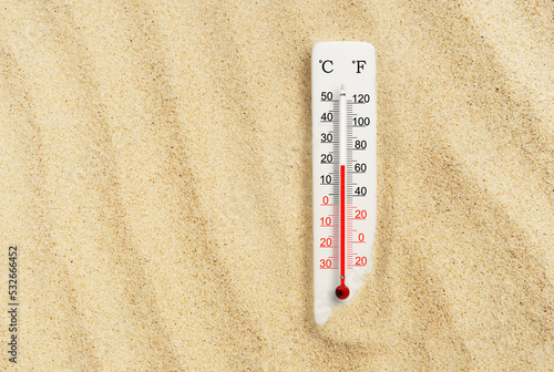 Hot summer day. Celsius and fahrenheit scale thermometer in the sand. Ambient temperature plus 19 degrees