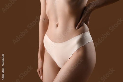 Slim young woman in underwear on brown background, closeup