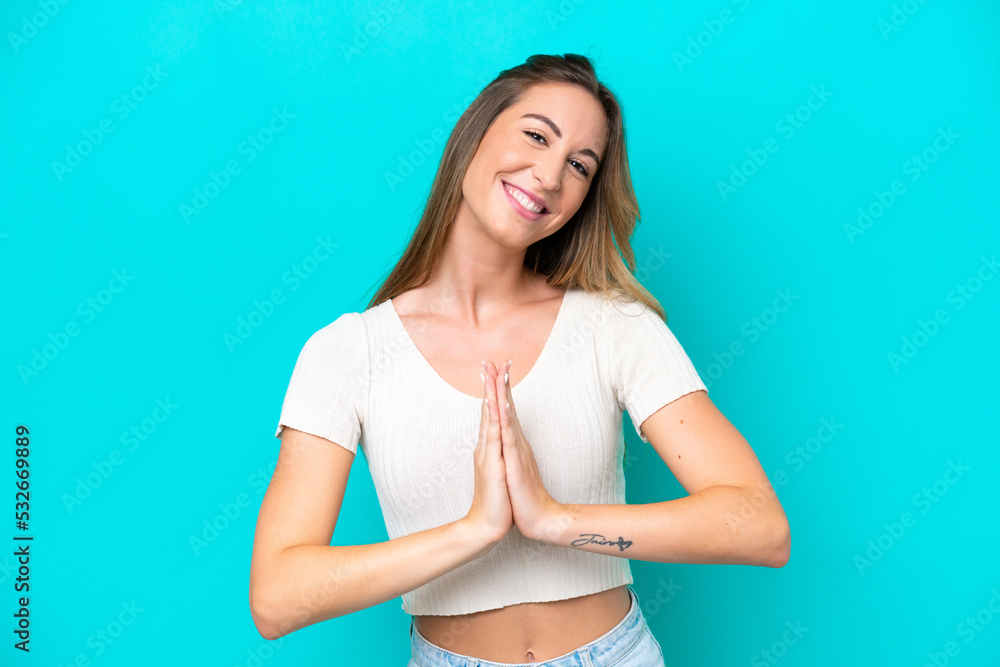 Young caucasian woman isolated on blue background keeps palm together. Person asks for something Young caucasian woman isolated on blue background keeps palm together. Person asks for something