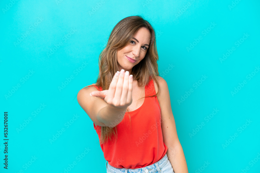 Fototapeta premium Young caucasian woman isolated on blue background inviting to come with hand. Happy that you came