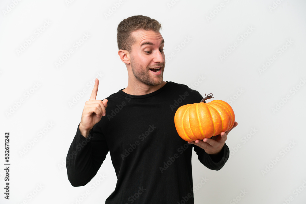 Young caucasian man holding a pumpkin isolated on white background intending to realizes the solution while lifting a finger up Young caucasian man holding a pumpkin isolated on white background intending to realizes the solution while lifting a finger up