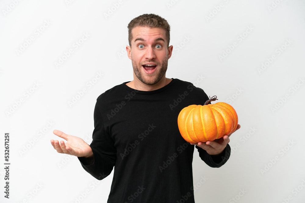 Young caucasian man holding a pumpkin isolated on white background with shocked facial expression Young caucasian man holding a pumpkin isolated on white background with shocked facial expression