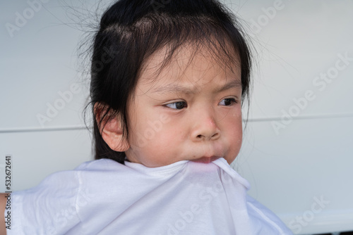 Obraz na plátně Portrait cute girl pulls her mouth over collar of her t shirt