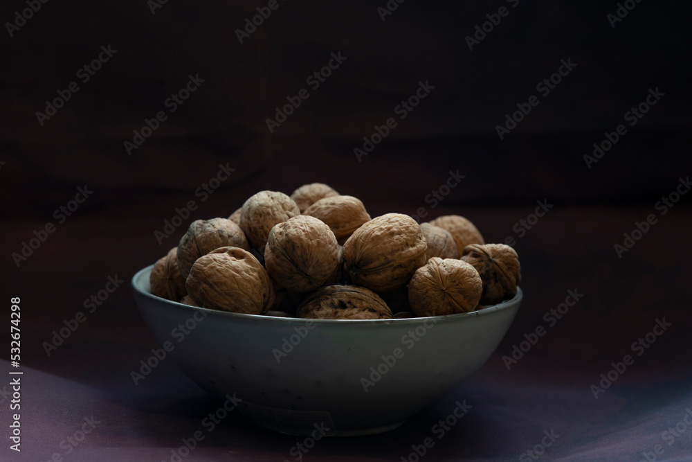 Bowl full of walnuts on black background with copy space Bowl full of walnuts on black background with copy space