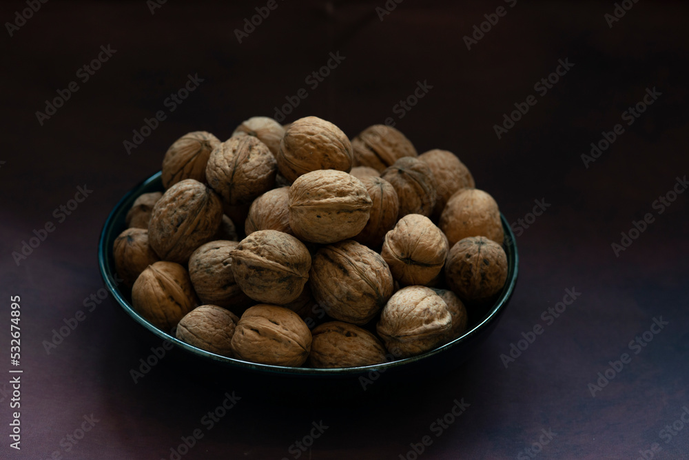 Bowl full of walnuts on black background with copy space Bowl full of walnuts on black background with copy space