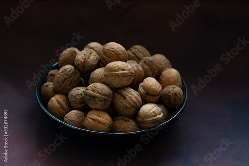 Bowl full of walnuts on black background with copy space