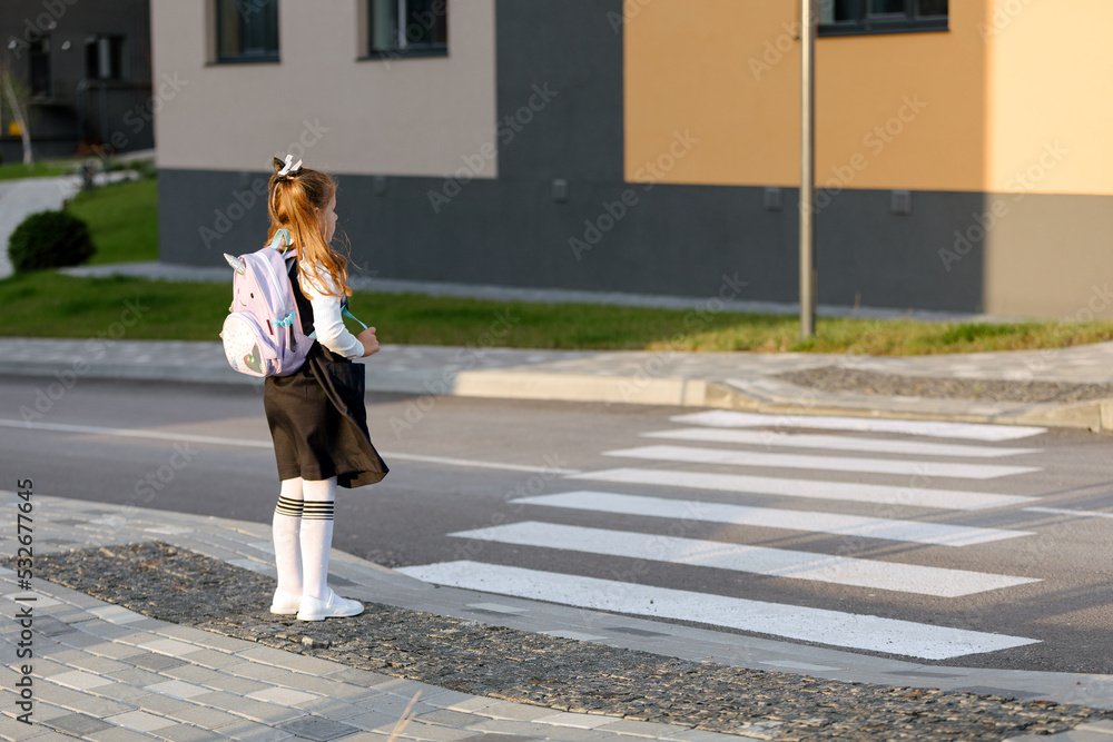 schoolgirl crosses the road at a pedestrian crossing