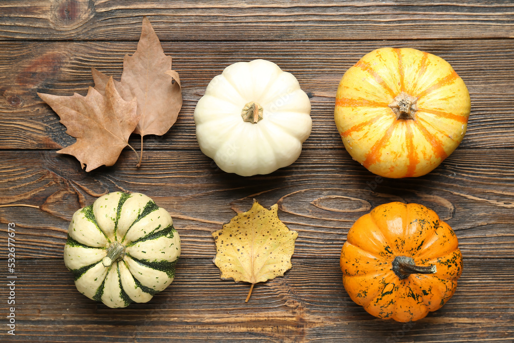 Composition with Halloween pumpkins and autumn leaves on wooden background