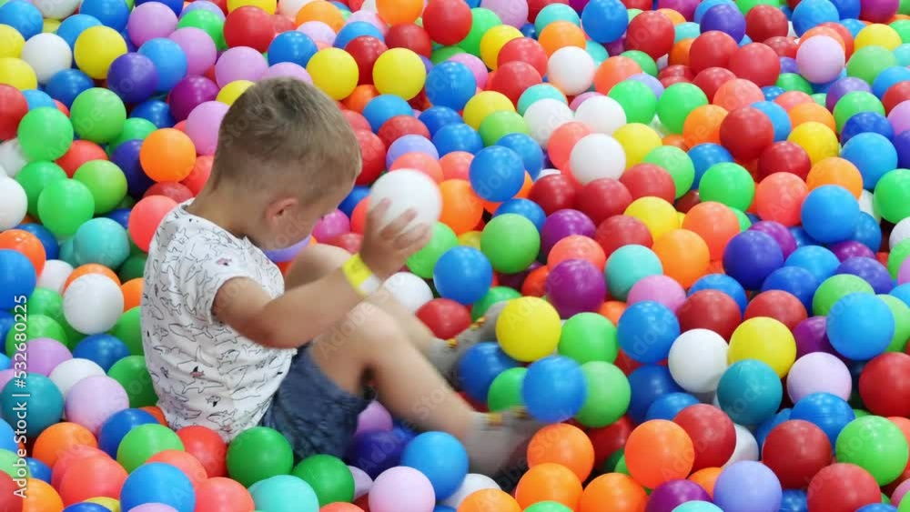 little boy lying on multi coloured plastic balls in pool in playing centre. little boy lying on multi coloured plastic balls in pool in playing centre.