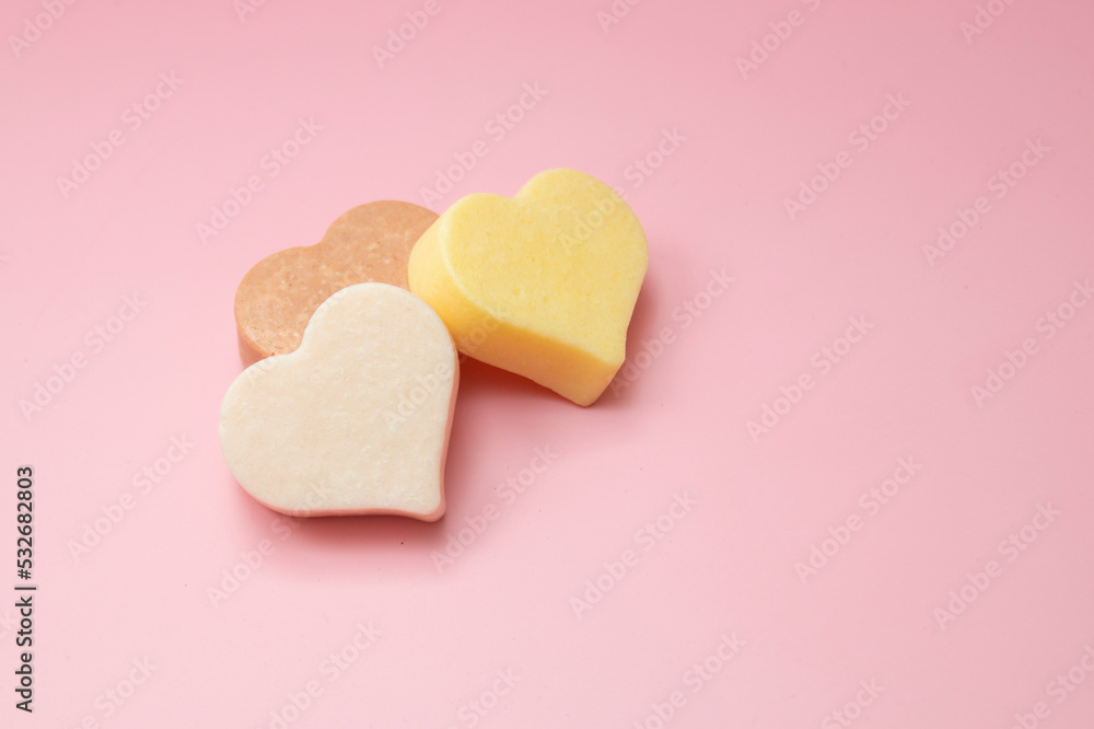 Obraz premium Heart shaped pink bar of soap on a light pink background. Top view, copy space. Heart shaped soaps. Importance of personal hygiene care. Copy space.