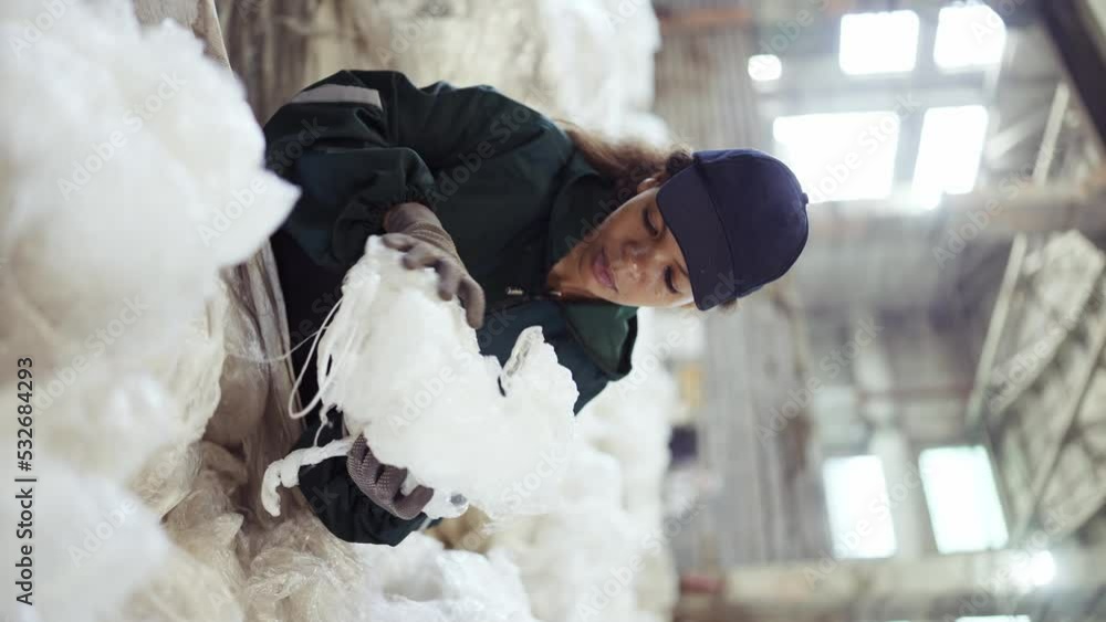 An African-American woman in a special uniform sorts polyethylene at a waste recycling plant. Processing of raw materials, recycling. Pollution control An African-American woman in a special uniform sorts polyethylene at a waste recycling plant. Processing of raw materials, recycling. Pollution control