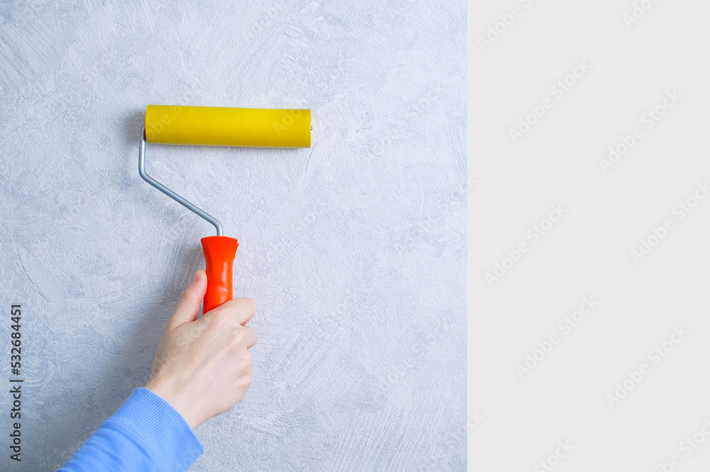Paste gray wallpaper. Roller rolling wallpaper in the hand of a