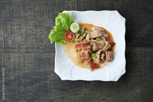 Stir-fried Pork belly with shrimp paste sauce and  stink beans. Thinly sliced ​​pork belly stir-fried with red chilli and green sataw in shrimp paste sauce served in a white plate with fresh vegetable photo