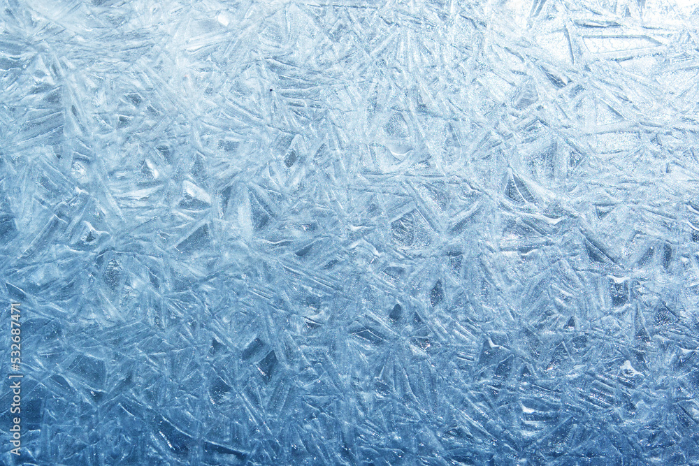 The texture of the ice surface. Winter background, festive background in the form of ice crystals, in natural deep blue color. The texture of the ice surface. Winter background, festive background in the form of ice crystals, in natural deep blue color.