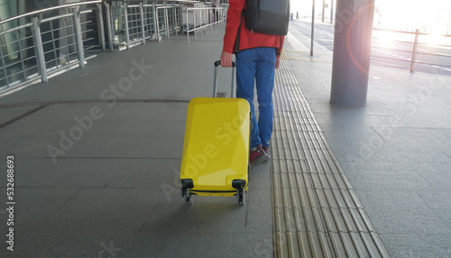 Travel trip with young man holding yellow luggage as looking the airplane in the hall room in the Airport terminal