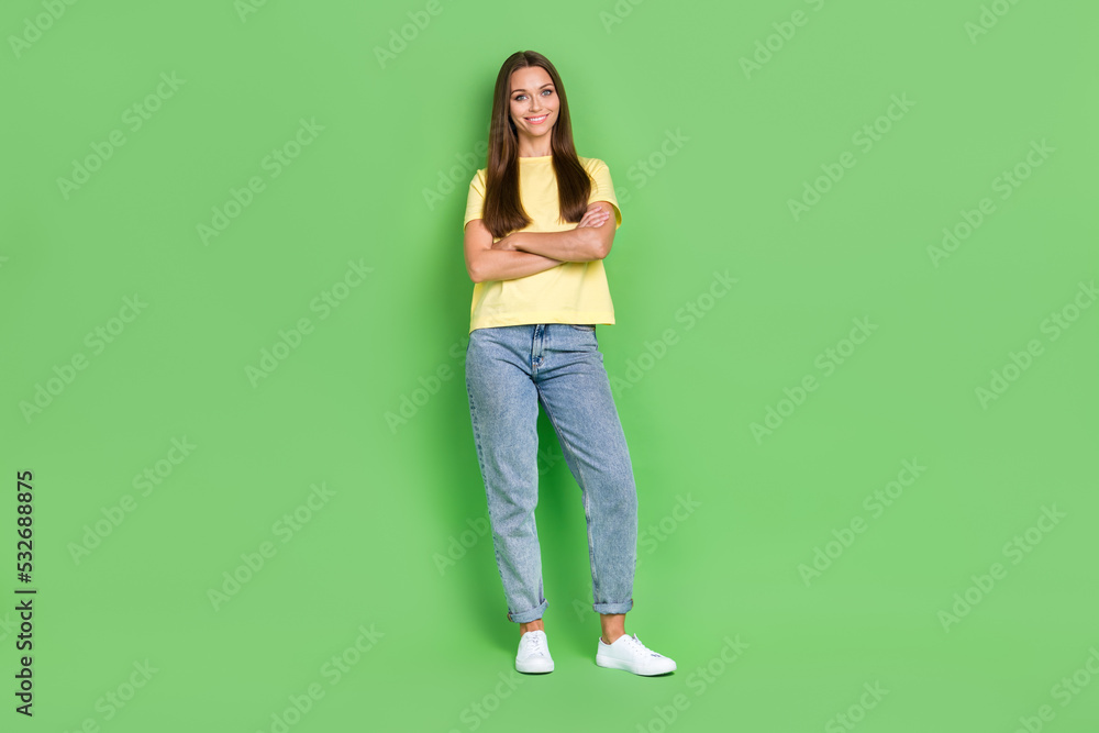 Full length photo of adorable nice lady dressed stylish yellow outfit arm folded stand empty space isolated on green color background Full length photo of adorable nice lady dressed stylish yellow outfit arm folded stand empty space isolated on green color background