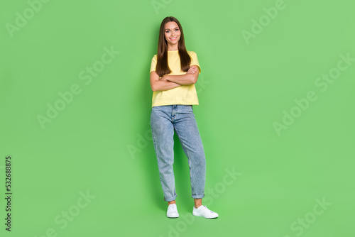 Full length photo of adorable nice lady dressed stylish yellow outfit arm folded stand empty space isolated on green color background