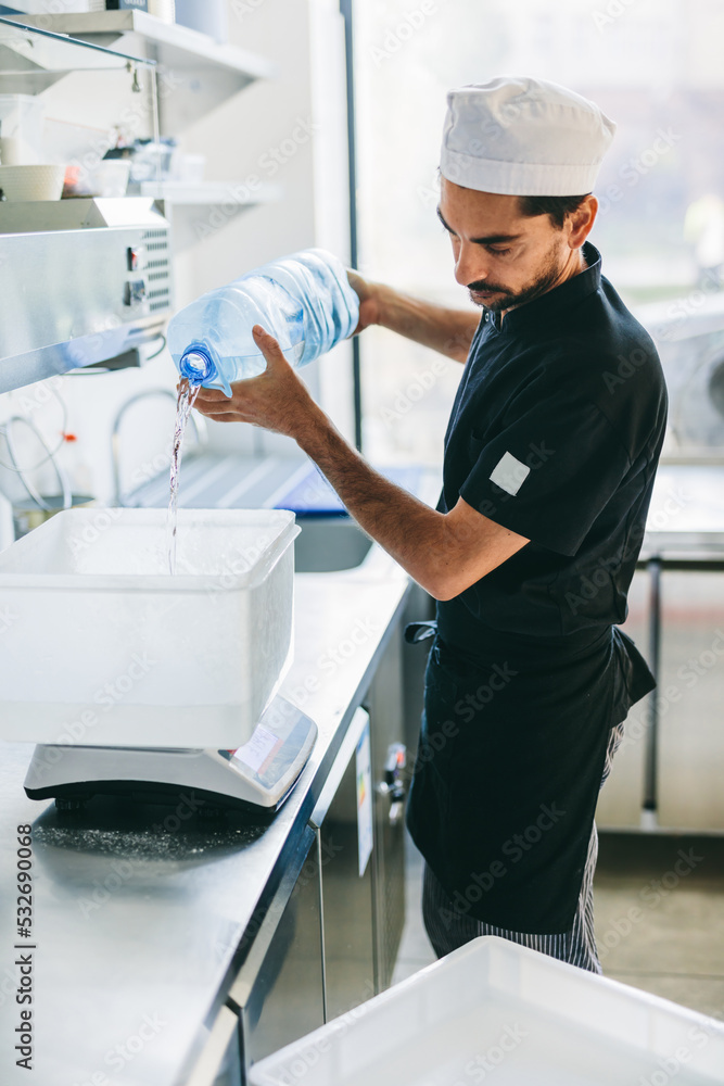 Obraz premium Italian chef pizzaiolo preparing pizza dough in restaurant kitchen