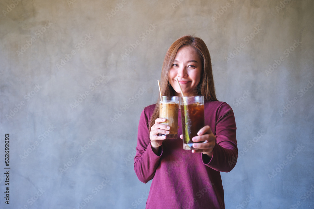 Portrait image of a young woman holding and serving two glasses of iced coffee Portrait image of a young woman holding and serving two glasses of iced coffee
