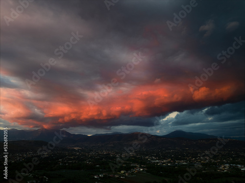 View from above, stunning aerial view of a dramatic sunset with beautiful clouds over a mountain range.