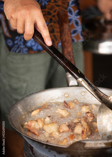 Close up a woman cooking of krenyos,  a popular traditional food from bantul yogyakarta. made from goat fat fried with garlic and salt.  photo