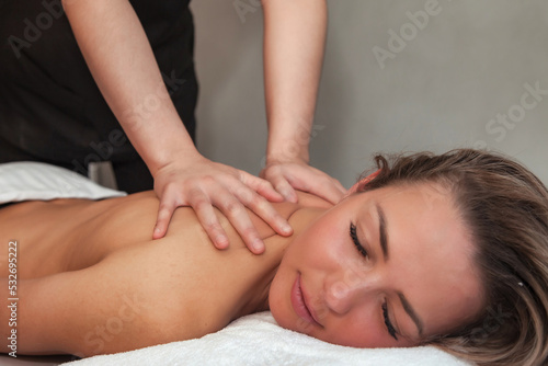 Massaging therapist makes back therapy massage for woman. Back massage female in SPA salon. Sensual healthy massaging in hands of professional masseur. Concept of healthy lifestyle and beauty