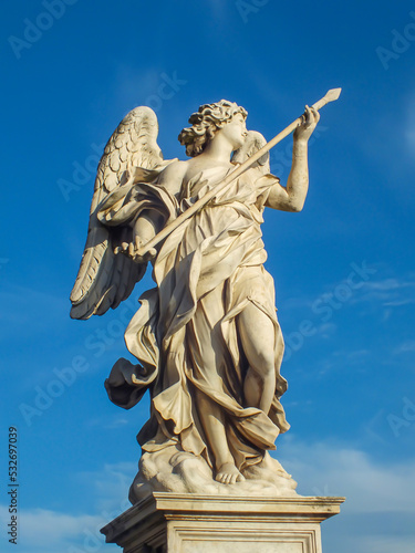 Statue of a holy angel with wings holding a war spear at the Saint Angel bridge on sky, Rome, Italy.