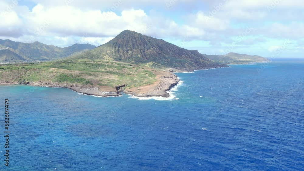 A drone shot of an ocean waves splash against rock on island. An amazing view of deep blue ocean with clear sky background A drone shot of an ocean waves splash against rock on island. An amazing view of deep blue ocean with clear sky background
