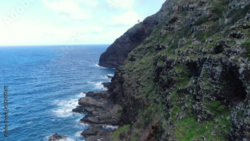 Amazing coastal views from the black volcanic sea cliffs of Makapu'u Lighthouse. Aerial pan away shot revealing the jagged lava rock walls above the the rocky seashores. photo