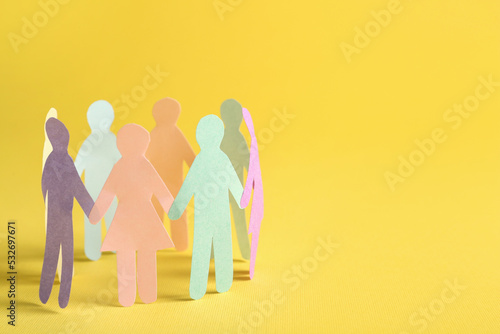 Many different paper human figures standing in circle on yellow background, space for text. Diversity and inclusion concept