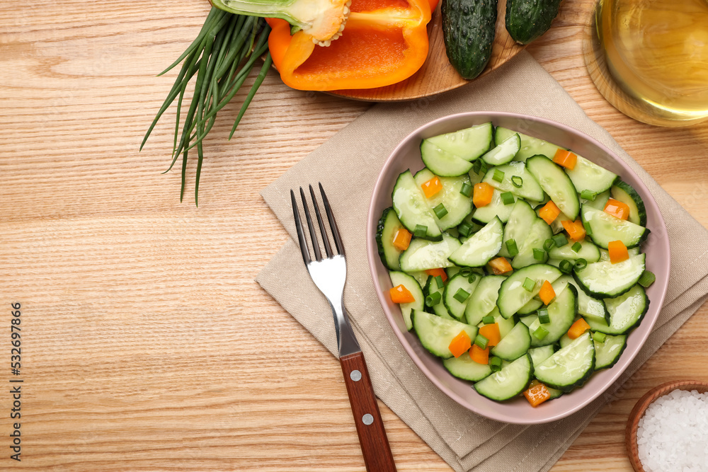 Tasty fresh salad with cucumber served on wooden table, flat lay. Space for text Tasty fresh salad with cucumber served on wooden table, flat lay. Space for text