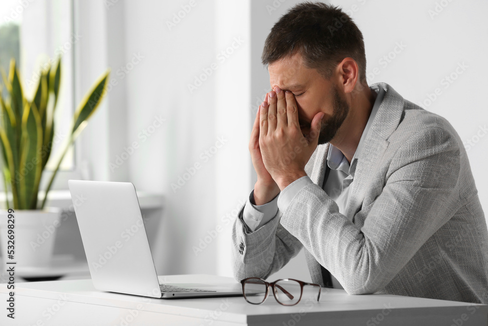 Man suffering from eyestrain at desk in office Man suffering from eyestrain at desk in office