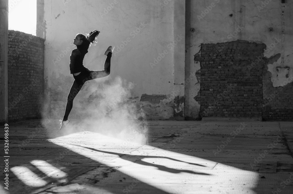 Ballerina dancing in an abandoned building on a sunny day in black and white - obrazy, fototapety, plakaty 
