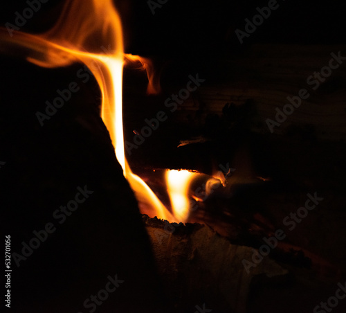 Flame in the fireplace against a dark background. Fire wood in the fireplace.