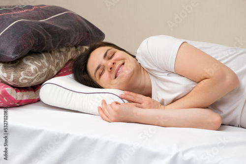 A woman sleeps on an orthopedic pillow made of memory foam, choosing it instead of other pillows made of fluff and sintepon