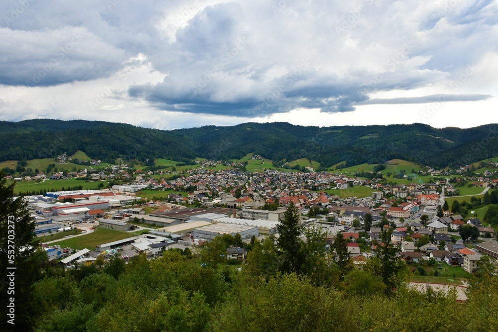 View of the town of Ziri in Gorenjska, Slovenia and forest covered hills above with clouds in the sky