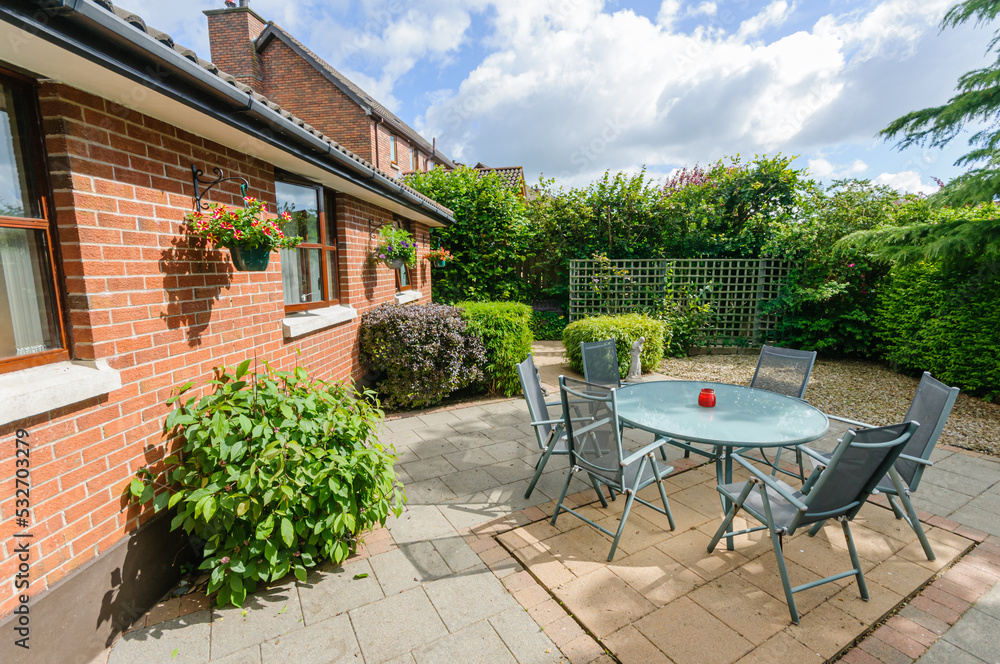 Modern patio with a table, chairs and barbeque behind a bungalow and sunroom. Modern patio with a table, chairs and barbeque behind a bungalow and sunroom.