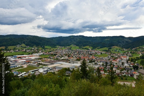 View of the town of Ziri in Gorenjska, Slovenia and forest covered hills above with clouds in the sky