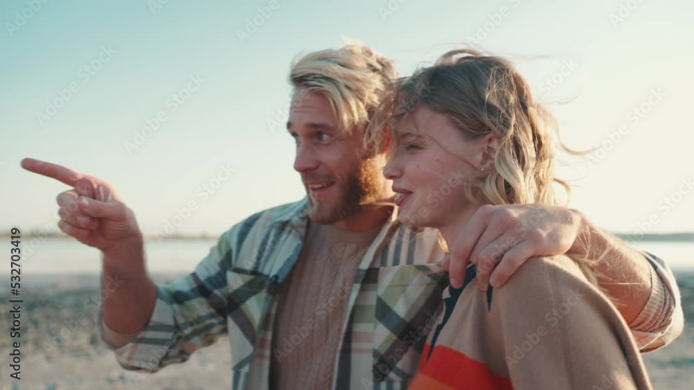 Laughing blond couple pointing finger and walking near estuary outdoors Laughing blond couple pointing finger and walking near estuary outdoors