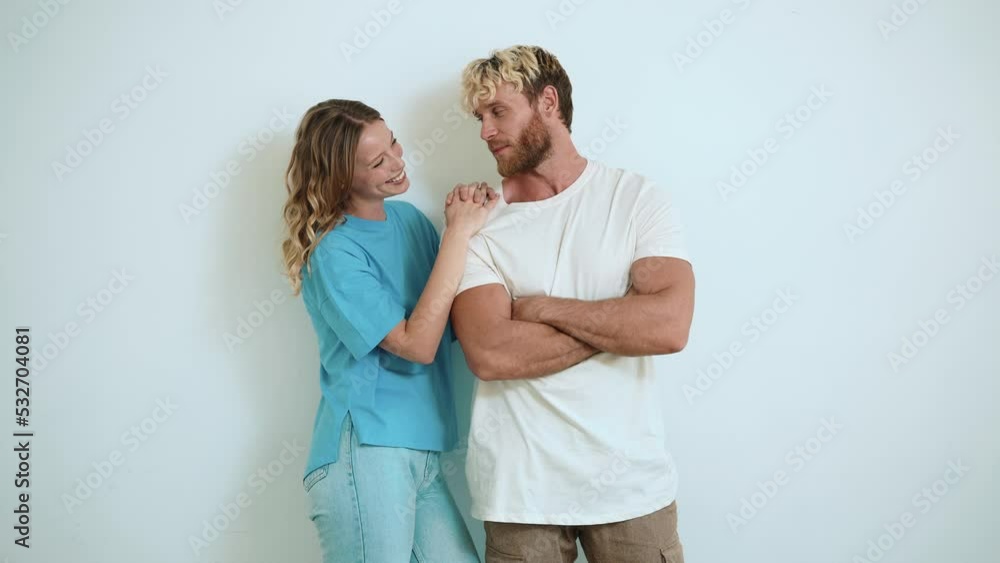 Smiling blond young couple hugging and looking at each other in the white studio Smiling blond young couple hugging and looking at each other in the white studio