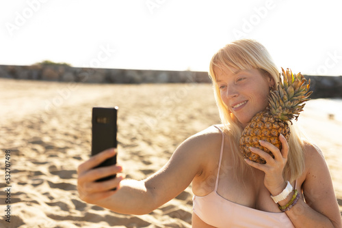 Cheerful young woman enjoy at tropical sand beach. Young woman taking selfie photo. photo