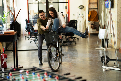 Colleagues in office. Businesswoman and businessman with bicycle. Two friends having fun together. © JustLife