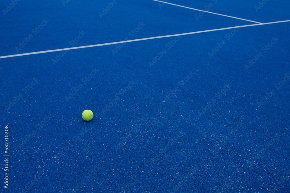 a ball on a blue paddle tennis court, racket sports