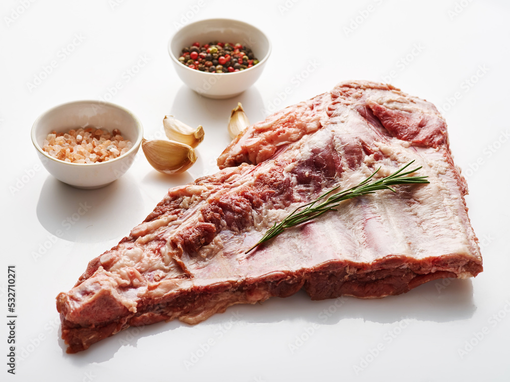Raw pork ribs on white background with spices and rosemary. Fresh pork. Spareribs.